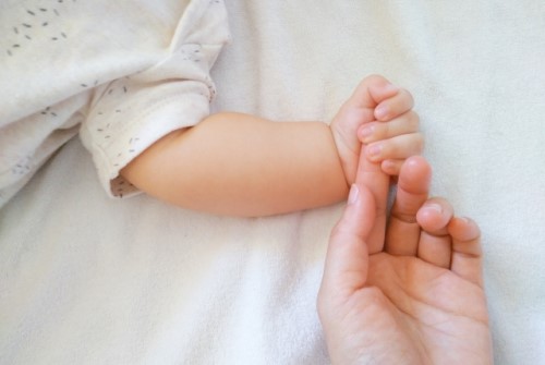 赤ちゃんがママの手を握りしめている