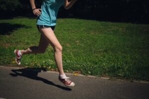 緑に囲まれた道をジョギングをする女性
